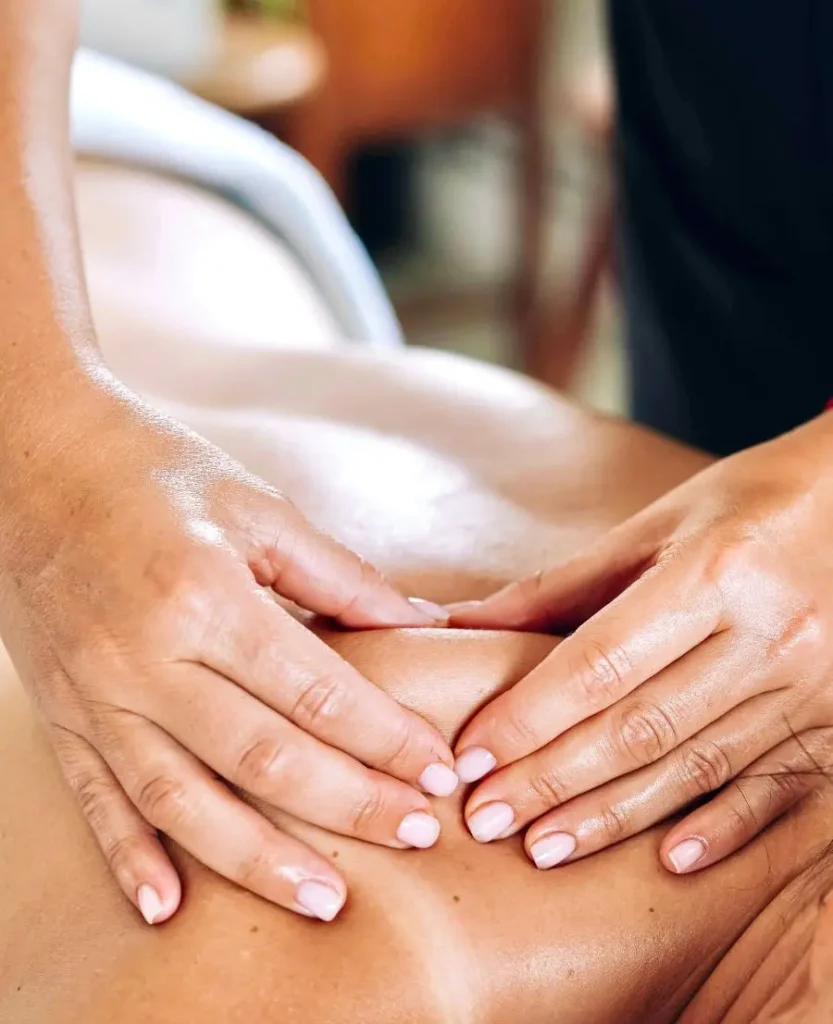 Close-up van handen die een therapeutische massage toepassen op de schouder en bovenrug van een persoon, met focus op het verlichten van spierspanning in een rustige omgeving.